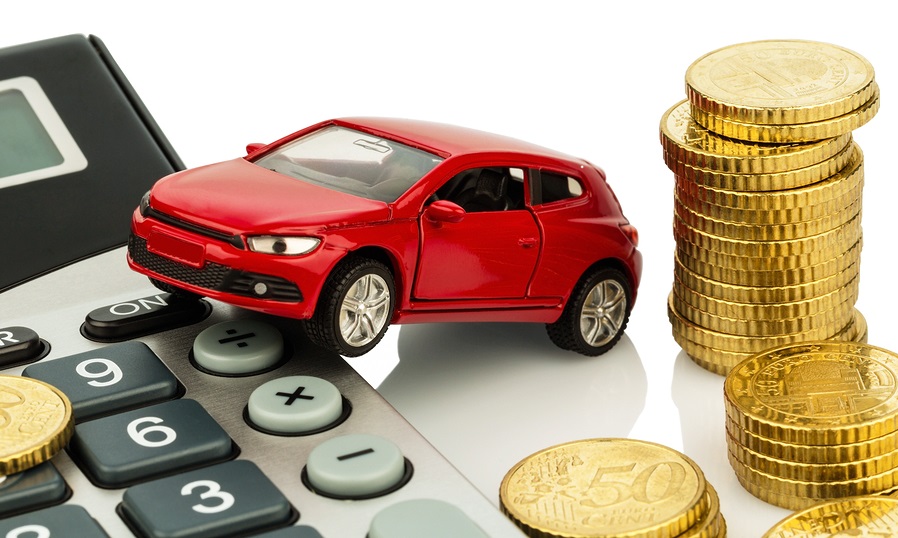 A imagem mostra um carro em cima de uma calculadora, com algumas moedas ao lado